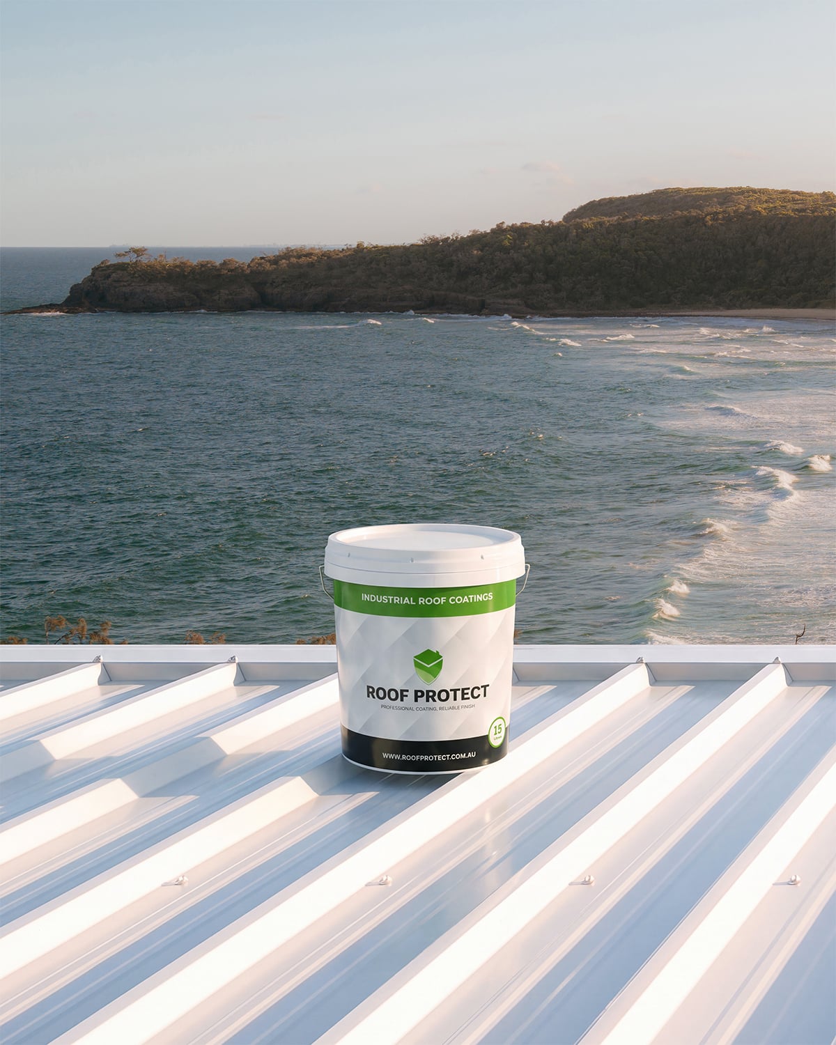 Roof Protect bucket with a green label on a white metal roof overlooking the coast.