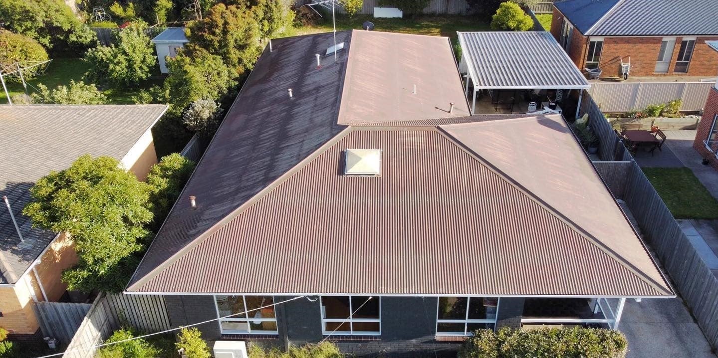 Weathered brown corrugated metal roof before restoration.