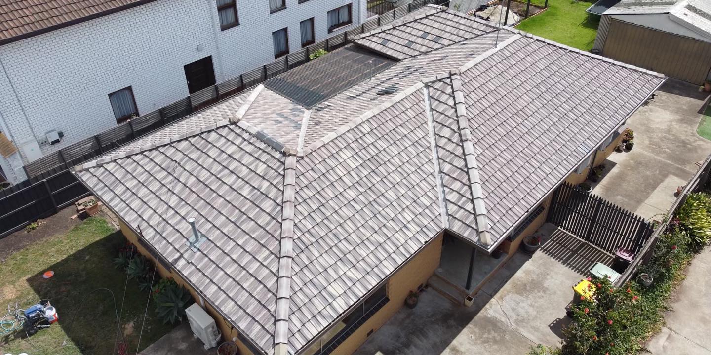 Weathered tiled roof with patchy surface colour before restoration.